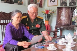 Đại tá Trịnh Xuân Ứng xem lại những kỷ vật xưa. (Ảnh: Hải Yến/TTXVN)