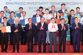 Thủ tướng Nguyễn Xuân Phúc, nguyên Chủ tịch nước Nguyễn Minh Triết và các doanh nghiệp nhận giấy chứng nhận đăng ký đầu tư, quyết định chủ trương đầu tư vào tỉnh Bình Phước. (Ảnh Thống Nhất/TTXVN)