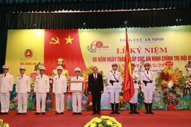 Thừa ủy quyền Chủ tịch nước, Phó Thủ tướng Thường trực Chính phủ Trương Hòa Bình gắn và trao Bằng Huân chương Chiến công hạng Ba lên lá cờ truyền thống của Cục An ninh chính trị nội bộ. (Nguồn: Bộ Công an)