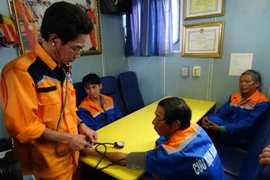 Chăm sóc y tế cho ngư dân khi vừa được đưa về bờ. (Ảnh: Trần Lê Lâm/Vietnam+)