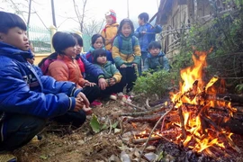 Học sinh co ro bên đống lửa. (Ảnh: Quốc Đạt/TTXVN)