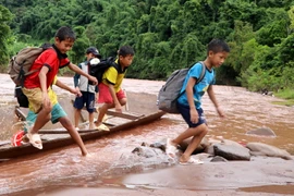 Học sinh phải đi thuyền vượt qua 2 con suối chảy xiết tới trường dự Lễ khai giảng năm học mới. (Ảnh: Việt Hoàng/TTXVN)