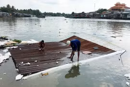 Người dân tháo dỡ tài sản bị chìm dưới sông do sạt lở. (Ảnh: Thanh Liêm/TTXVN)
