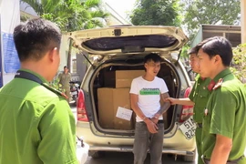 Lực lượng công an khám xét đối tượng vận chuyển hàng lậu. (Ảnh: Nguyễn Văn Việt/TTXVN)