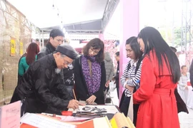 Viết thư pháp tại Hội Sách Xuân Mậu Tuất. (Ảnh: Võ Dung/TTXVN)