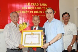 Bí thư Thành ủy Thành phố Hồ Chí Minh Nguyễn Thiện Nhân và lãnh đạo huyện Hóc Môn trao Huy hiệu 70 năm tuổi Đảng cho đảng viên Lê Văn Nghị. (Ảnh: Thanh Vũ/TTXVN)