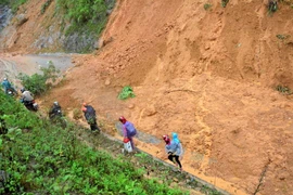 Người dân khó khăn khi di chuyển qua điểm sạt lở. (Ảnh: Văn Dũng/TTXVN)