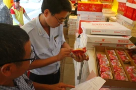 Đoàn kiểm tra đối chiếu chỉ tiêu chất lượng do nhà sản xuất công bố và thực tế trên bánh Trung Thu. (Ảnh: Đinh Hằng/TTXVN)