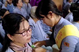 Các Phật tử thực hành Nghi thức Bông hồng cài áo tại buổi lễ Vu Lan báo hiếu tại Cà Mau. (Ảnh: Kim Há/TTXVN)
