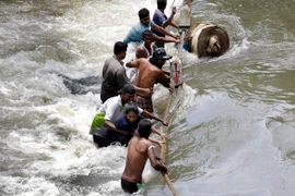 Người dân cố gắng vượt qua dòng nước lũ hoành hành tại Sedawatte, ngoại ô thủ đô Colombo, Sri Lanka. (Nguồn: EPA/TTXVN)