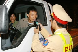 Cảnh sát giao thông kiểm tra nồng độ cồn của lái xe. (Ảnh: Doãn Tấn/TTXVN)