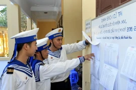 Cán bộ, chiến sỹ đảo Song Tử Tây xem danh sách niêm yết cử tri. (Ảnh: Phạm Kiên/TTXVN)