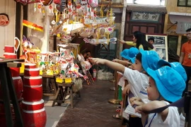 Các cháu thiếu nhi tham quan gian hàng đồ chơi trung thu truyền thống. (Ảnh: Đinh Thuận/TTXVN)
