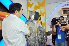 Chủ tịch HĐQT Đường Nhất Lâm tiến hành thí nghiệm về tính dẫn điện của bộ quần áo. (Ảnh: Vĩnh Hà/Vietnam+)