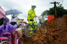 Lực lượng Cảnh sát giao thông giúp các em học sinh di chuyển qua điểm sạt lở để tới trường. (Ảnh: Xuân Tư/TTXVN)