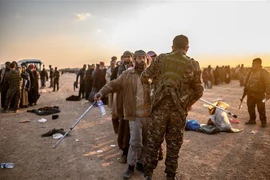 Các tay súng Tổ chức nhà nước Hồi giáo (IS) tự xưng đầu hàng Lực lượng Dân chủ Syria do Mỹ hậu thuẫn tại dinh lũy cuối cùng ở Baghouz, tỉnh Deir Ezzor, miền Đông Syria ngày 22/2/2019. (Ảnh: AFP/TTXVN)