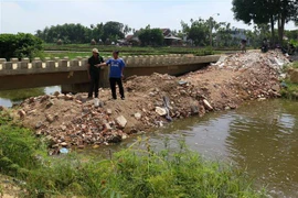 Người dân đổ đất lấp ngang đoạn kênh qua địa bàn thôn Điền Chánh Trung. (Ảnh: Phước Ngọc/TTXVN)