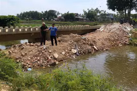 Người dân đổ đất lấp ngang đoạn kênh qua địa bàn thôn Điền Chánh Trung. (Ảnh: Phước Ngọc/TTXVN)