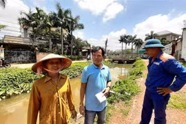 Anh Trung Kiên con trai bà Nguyễn Thị Hoa ( áo xanh ở giữa) trao đổi về việc mẹ hiến căn nhà và đất cho chính quyền cải tạo suối Đồng Tiền. (Ảnh: Dương Chí Tưởng/TTXVN)