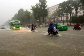 Nhiều tuyến đường thành phố Vinh bị ngập sâu khiến các phương tiện tham gia giao thông gặp nhiều khó khăn. (Ảnh: Tá Chuyên/TTXVN)