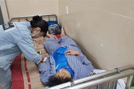 Người nhà chăm sóc cho cháu Phạm Công Khanh, người bị giáo viên dạy võ đánh vỡ xương hàm. (Ảnh: Minh Thu/TTXVN)