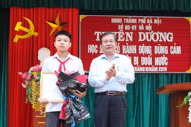 Phó Giám đốc Sở Giáo dục và Đào tạo Hà Nội Lê Ngọc Quang trao Bằng khen của Chủ tịch Ủy ban Nhân dân thành phố Hà Nội cho em Phan Trung Hiếu. (Ảnh: Thanh Tùng/TTXVN)