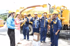 Lãnh đạo Công ty TNHH MTV Thoát nước Hà Nội phát nước uống, động viên người lao động làm việc trong những ngày nắng nóng. (Ảnh: Mạnh Khánh/TTXVN)