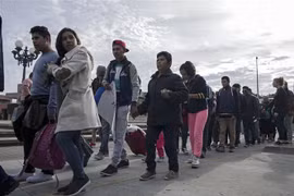Người di cư Trung Mỹ vượt qua hàng rào biên giới khi di chuyển từ Tijuana, bang Baja California (Mexico) tới San Diego, Mỹ, ngày 21/3/2019. (Ảnh: AFP/TTXVN)