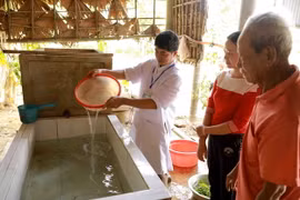 Nhân viên Trung tâm Y tế dự phòng huyện Lệ Thủy, tỉnh Quảng Bình tiến hành khử khuẩn nước sinh hoạt bằng dung dịch Cloramin B cho hộ dân. (Ảnh: Vũ Sinh/TTXVN)