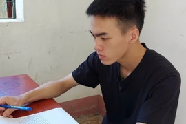 Đối tượng Triệu Tiến Mạnh viết lời khai tại cơ quan công an. (Ảnh: TTXVN phát)