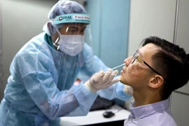 Nhân viên y tế lấy mẫu dịch xét nghiệm COVID-19 cho người dân tại Singapore ngày 30/10 vừa qua. (Ảnh: AFP/TTXVN)