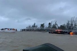 Lực lượng chức năng tại hiện trường khống chế đám cháy và di chuyển các thuyền tới khu vực an toàn. (Ảnh: Đoàn Hữu Trung/TTXVN)