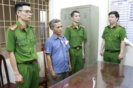 Lực lượng chức năng thi hành lệnh bắt tạm giam đối với Ngũ Ngọc Hưng - thứ 2 từ trái qua. (Ảnh: Đậu Tất Thành/TTXVN)