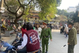 Công an phường Hàng Trống (Hoàn Kiếm) kiểm tra, nhắc nhở, xử lý phương tiện đỗ trái quy định trước đêm Noel. (Ảnh Mạnh Khánh/Vietnam+)