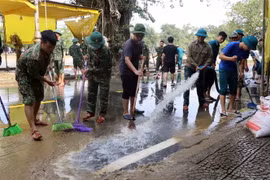 Các lực lượng tham gia dọn dẹp bùn non sau khi nước lũ rút tại nhiều tuyến đường của thành phố Huế. (Ảnh: Đỗ Trưởng/TTXVN)