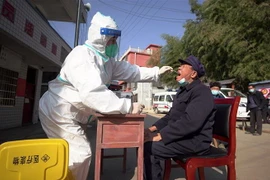 Nhân viên y tế lấy mẫu xét nghiệm COVID-19 cho người dân tại Quý Châu, Trung Quốc. (Ảnh: AFP/TTXVN)