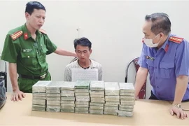 Đối tượng Chang A Sang trú tại bản Chuyên Gia 2, xã Nậm Kè, huyện Mường Nhé, tỉnh Điện Biên cùng tang vật 60 bánh heroin tại cơ quan điều tra. (Ảnh: TTXVN phát)