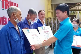 Ông Phạm Chí Tâm, Phó Chủ tịch Liên đoàn Lao động Thành phố Hồ Chí Minh trao tặng thẻ bảo hiểm y tế cho người lao động có hoàn cảnh khó khăn. (Ảnh: Thanh Vũ/TTXVN)