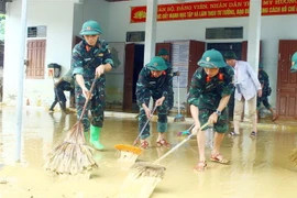 Cán bộ chiến sỹ Sư đoàn 324 đẩy bùn đất, vệ sinh tại nhà văn hóa thôn Mỹ Hươn, xã Thanh Mỹ, huyện Thanh Chương, tỉnh Nghệ An. (Ảnh: Tá Chuyên/TTXVN)