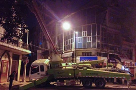 Chiếc xe cẩu bơm bê tông bất ngờ đổ nghiêng khi đang thi công khiến nhiều người dân hốt hoảng. (Ảnh: PV/Vietnam+)