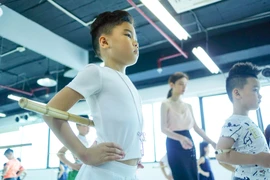 Các bài tập với gậy sẽ giúp các em tạo dáng đứng chuẩn và sửa dáng do ảnh hưởng từ ngồi học sai tư thế. (Ảnh: Minh Sơn/Vietnam+)