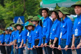 Hình ảnh những sinh viên tình nguyện Đại học Bách khoa lập ‘hàng rào sống’ giúp thí sinh sang đường gây ấn tượng với thí sinh và phụ huynh. (Ảnh: Minh Sơn/Vietnam+)