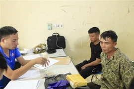Hai đối tượng cùng tang vật tại cơ quan điều tra. (Ảnh: Xuân Tư/TTXVN)