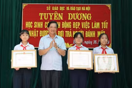 Phó Giám đốc Sở Giáo dục và Đào tạo Hà Nội Phạm Xuân Tiến trao Giấy khen của Giám đốc Sở cho 3 học sinh. (Ảnh: Thanh Tùng/TTXVN)