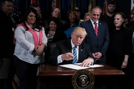 Tổng thống Mỹ Donald Trump (giữa) ký một sắc lệnh ở Washington, DC ngày 27/4. (Nguồn: AFP/TTXVN)