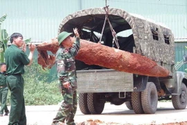 Lực lượng chức năng đang tiến hành di dời quả bom. (Ảnh: Trung Nguyên/TTXVN)