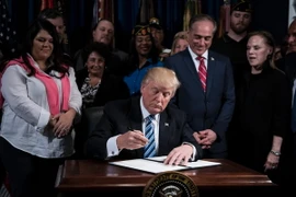  Tổng thống Mỹ Donald Trump (giữa) ký một sắc lệnh ở Washington, DC ngày 27/4. (Nguồn: AFP/TTXVN)