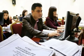 Cán bộ ngành bảo hiểm xã hội rà soát danh sách các hộ gia đình tham gia bảo hiểm y tế. (Ảnh: Trung Kiên/TTXVN)