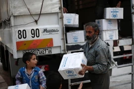 Người dân Syria nhận hàng cứu trợ tại khu vực Harasta, ngoại ô thủ đô Damascus. (Nguồn: AFP/TTXVN)