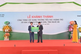 Ông Nguyễn Mỹ Hào-thành viên HĐQT Vietcombank trao biển tượng trưng số tiền 15 tỷ đồng tài trợ xây dựng Trường tiểu học Hoàng Trù. (Ảnh: Vietnam+)